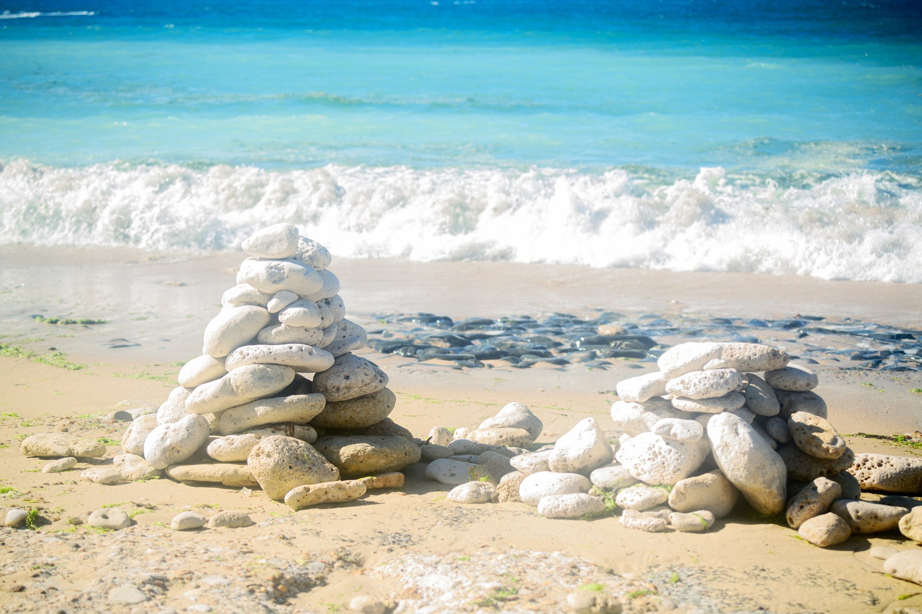 Deux cairns de galets blancs posés sur une plage de sable fin, face à l’océan Atlantique, sur l’île de Ré.