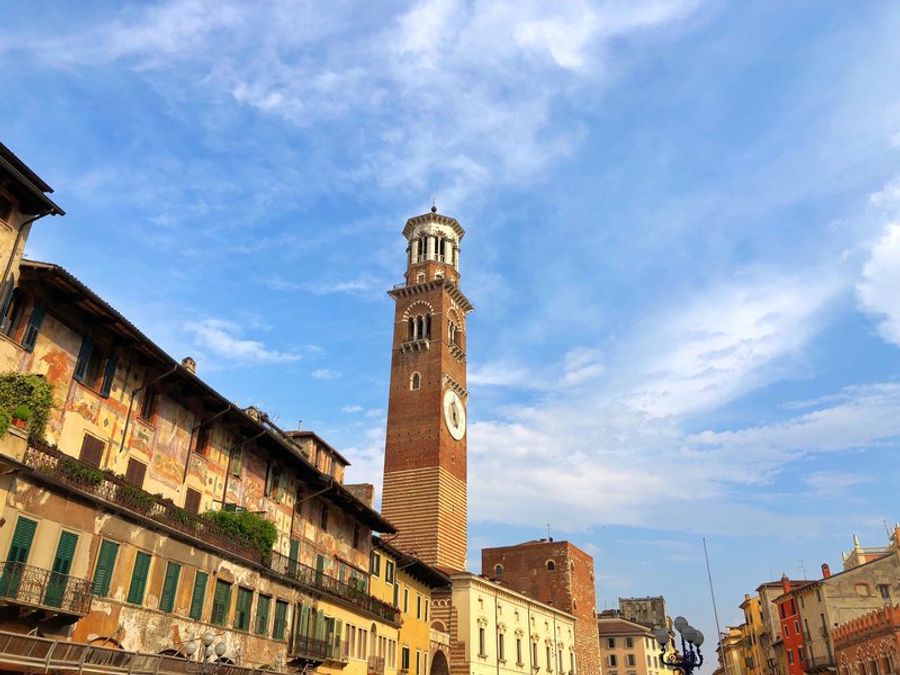 La tour des Lamberti se dressant fièrement au-dessus des toits de Vérone, un ciel bleu clair en arrière-plan.