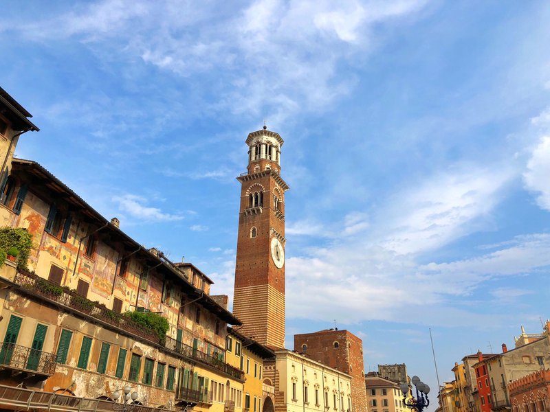 La tour des Lamberti se dressant fièrement au-dessus des toits de Vérone, un ciel bleu clair en arrière-plan.