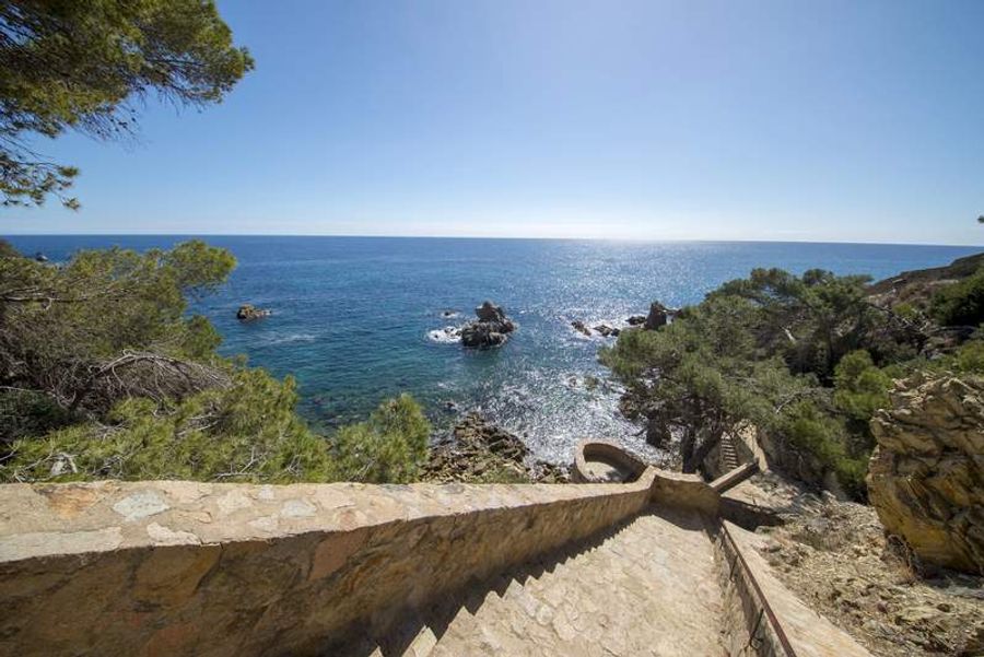 Escalier en pierre sur le chemin de ronde à Calella de Palafrugell, offrant une vue panoramique sur la mer Méditerranée.