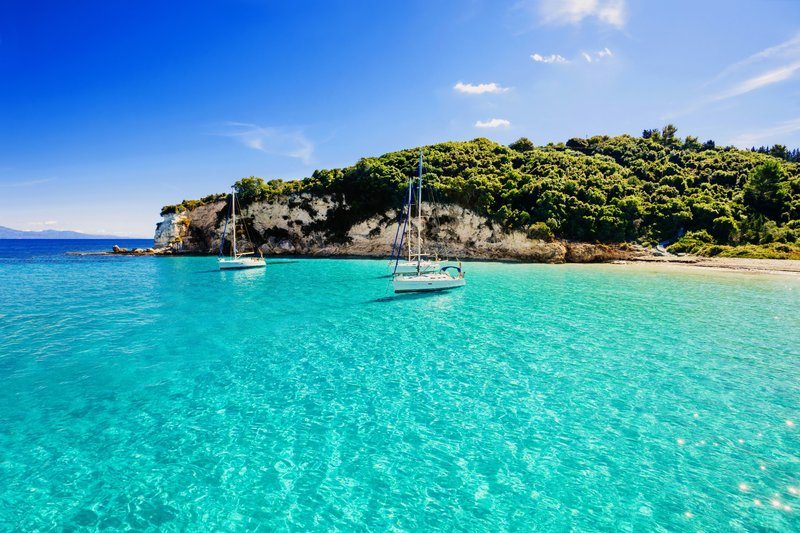 Eau turquoise et voiliers amarrés près des falaises verdoyantes de l