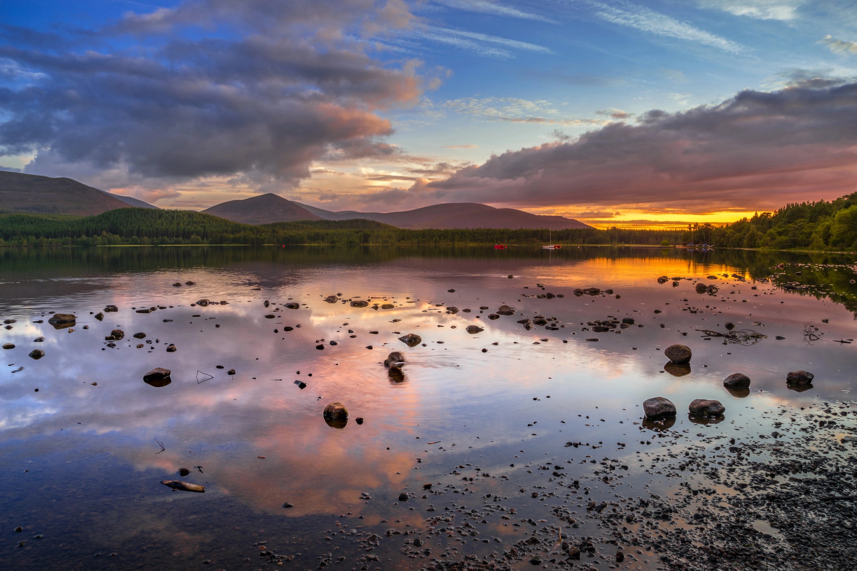 Le Loch Morlich bordé de pins calédoniens avec les montagnes du parc national des Cairngorms en arrière-plan