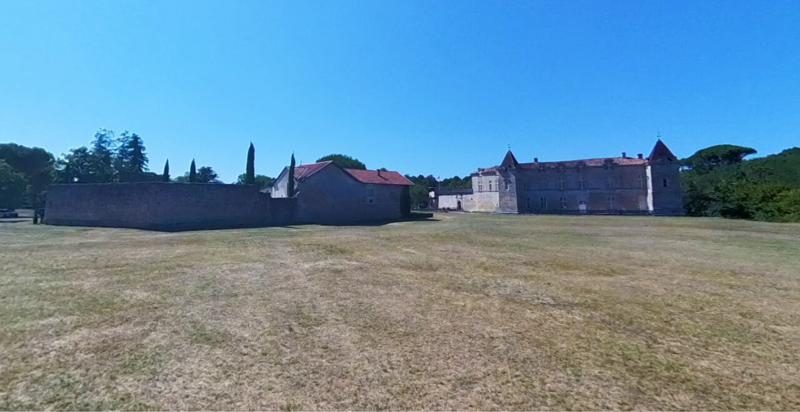 Vue du Château de Cazeneuve et de ses dépendances sous un ciel bleu, entouré d