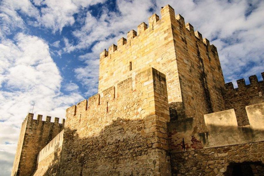 Murs du Château de São Jorge sous un ciel partiellement nuageux à Lisbonne, Portugal.