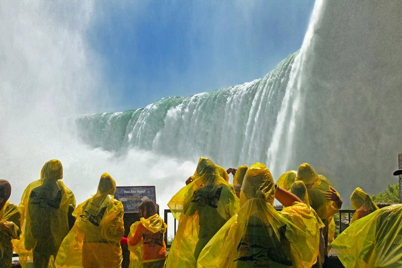 Vue rapprochée des chutes du Niagara avec des visiteurs portant des ponchos jaunes.