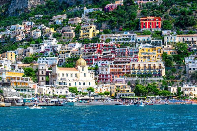 Vue panoramique de Positano sur la côte amalfitaine avec ses maisons colorées et la mer en avant-plan.
