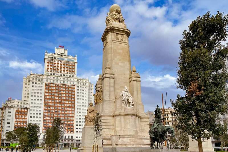 Monument à Cervantes à Madrid avec des statues de Don Quichotte et Sancho Panza en avant-plan, situé sur la Plaza de España avec l'hôtel Riu en arrière-plan.