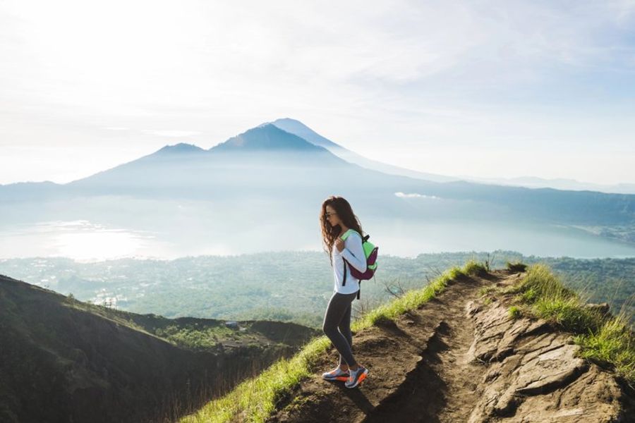 Randonneuse marchant sur un sentier avec vue sur le Mont Batur à Bali.