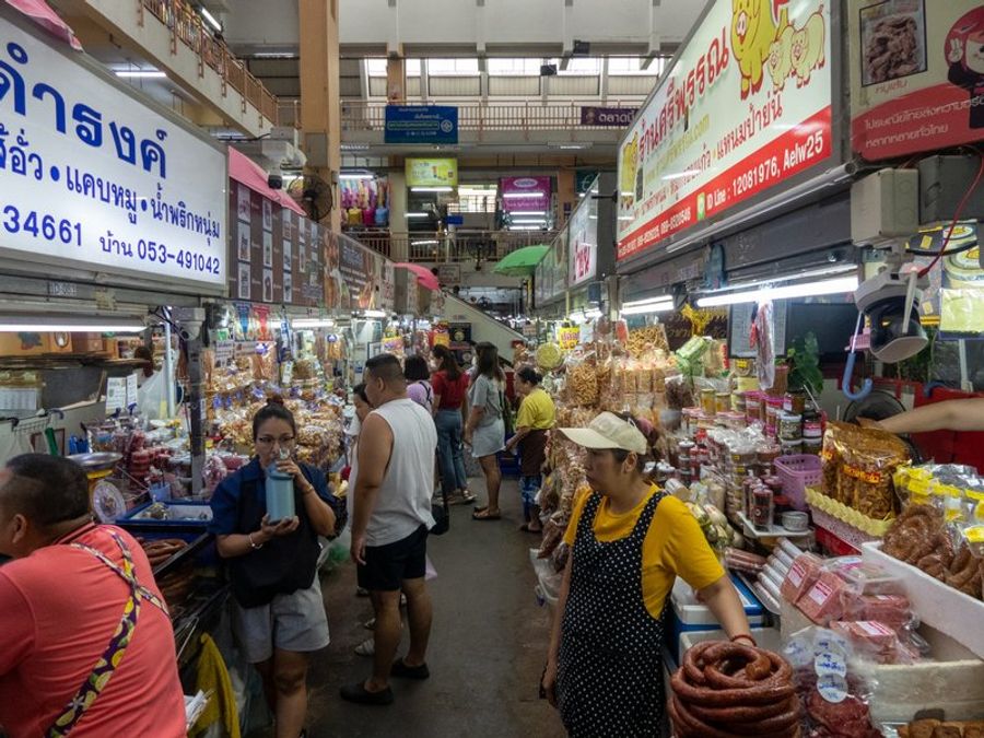 Intérieur animé du marché Warorot à Chiang Mai avec des vendeurs et des clients.