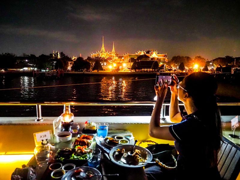 Femme prenant une photo depuis une croisière sur le Chao Phraya.