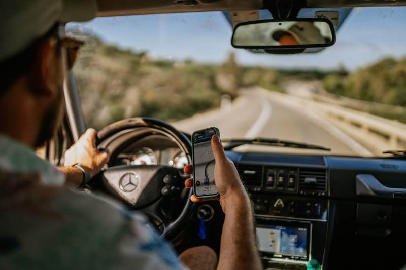 Conducteur consultant son GPS au volant lors d’un road trip en Europe sur une route de campagne