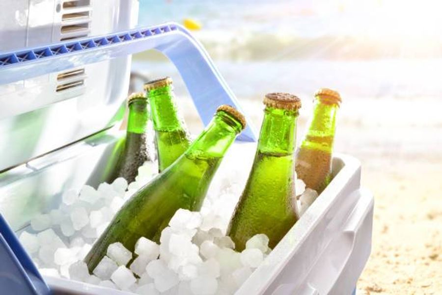 Bouteilles en verre plongées dans la glace à l’intérieur d’une glacière sur une plage ensoleillée