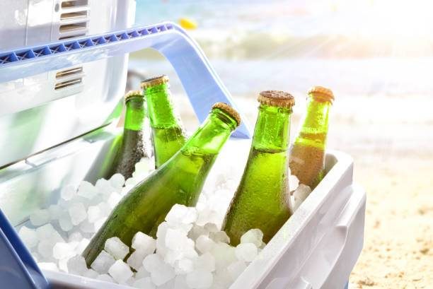 Bouteilles en verre plongées dans la glace à l’intérieur d’une glacière sur une plage ensoleillée