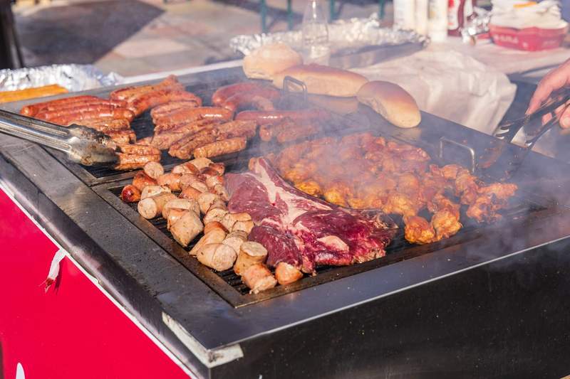 Barbecue extérieur à Tirana en Albanie avec saucisses grillées, brochettes, pièce de bœuf et morceaux de poulet marinés sur une grande plancha fumante