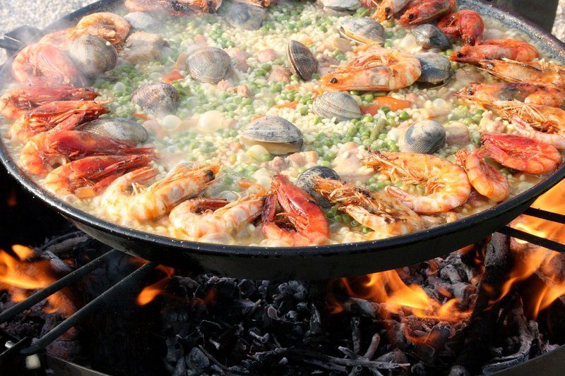 Paella traditionnelle catalane avec des fruits de mer, préparée sur un feu de bois.