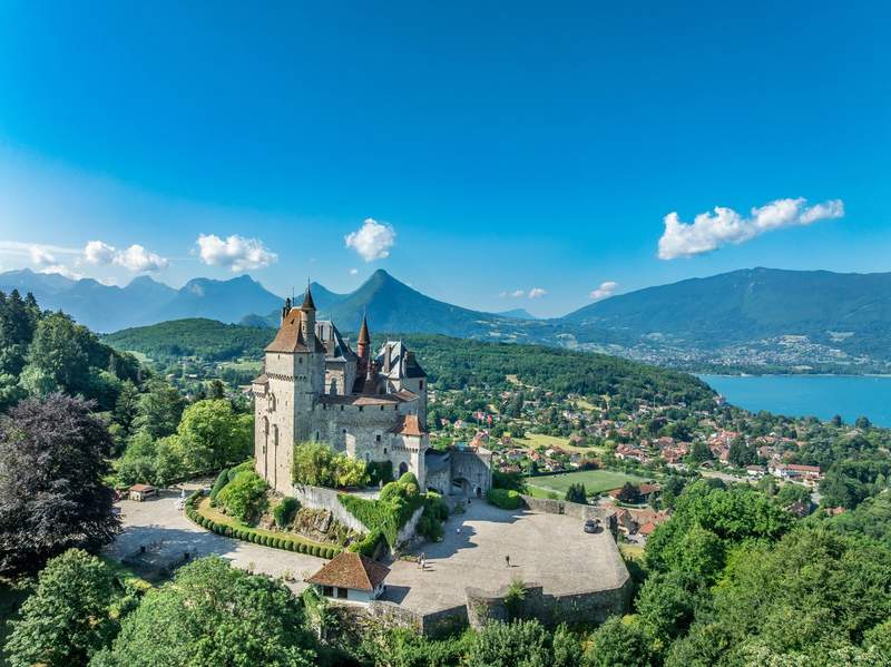 Château de Menthon-Saint-Bernard en Haute-Savoie avec vue sur le lac d’Annecy et les montagnes.
