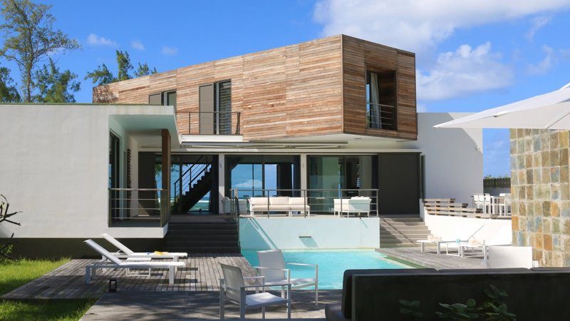 Belle villa moderne à l’Île Maurice avec une façade blanche et un jardin bien entretenu.