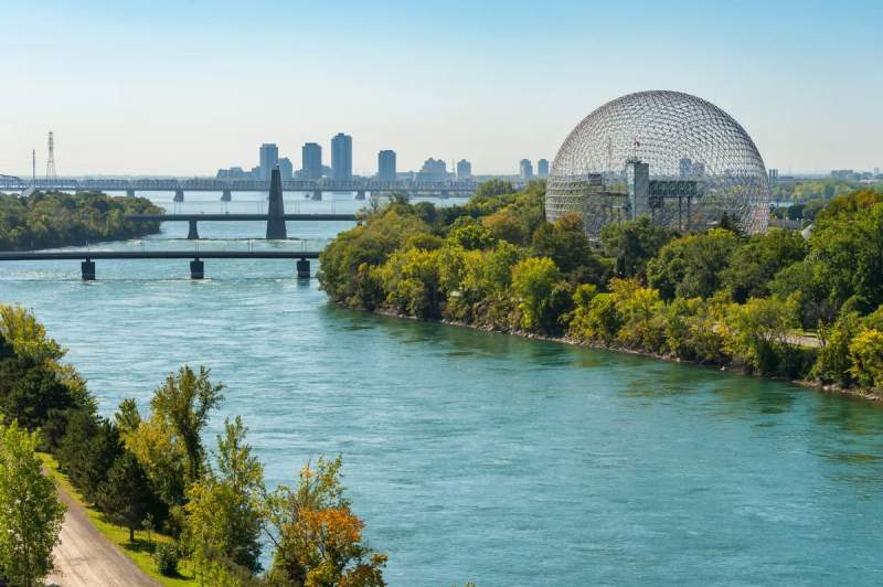 Vue de la biosphère sur l’Île Sainte-Hélène à Montréal, entourée de verdure et du fleuve Saint-Laurent.