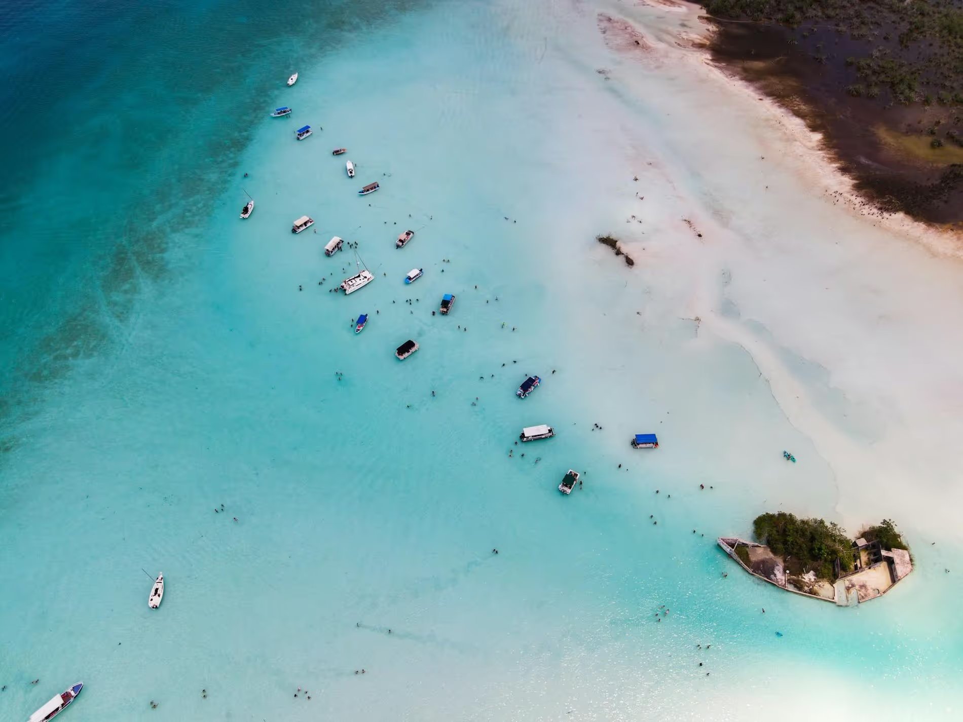 Bateaux de touristes ancrés près de la plage dans une eau turquoise.