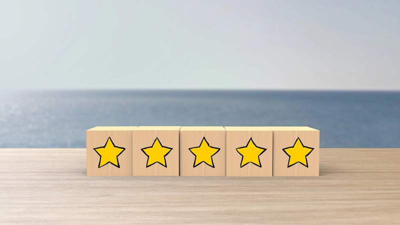 Blocs en bois alignés sur une table avec des étoiles jaunes dessinées dessus, symbolisant une évaluation ou un avis client positif.
