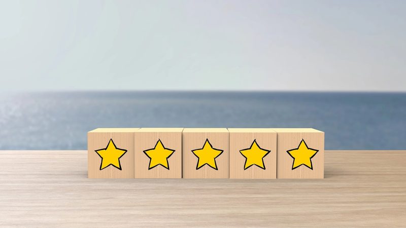 Blocs en bois alignés sur une table avec des étoiles jaunes dessinées dessus, symbolisant une évaluation ou un avis client positif.