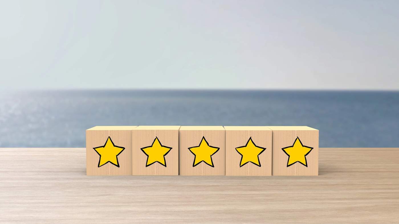 Blocs en bois alignés sur une table avec des étoiles jaunes dessinées dessus, symbolisant une évaluation ou un avis client positif.