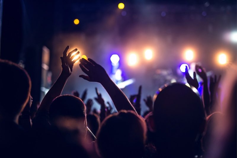 Des festivaliers levant les bras sous les lumières vibrantes d