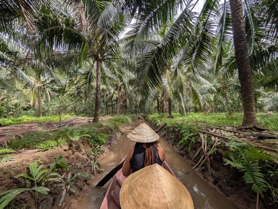 Balade traditionnelle en barque sur un canal étroit bordé de cocotiers à Ben Tre Vietnam.