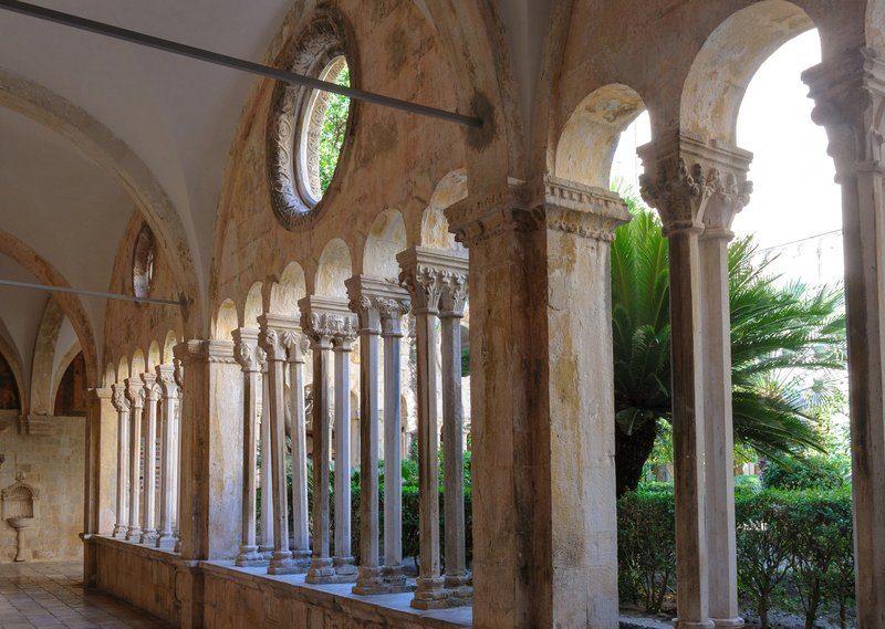 Cloître gothique du monastère franciscain de Dubrovnik avec ses colonnes de pierre finement sculptées et son jardin intérieur verdoyant, datant du XIVe siècle
