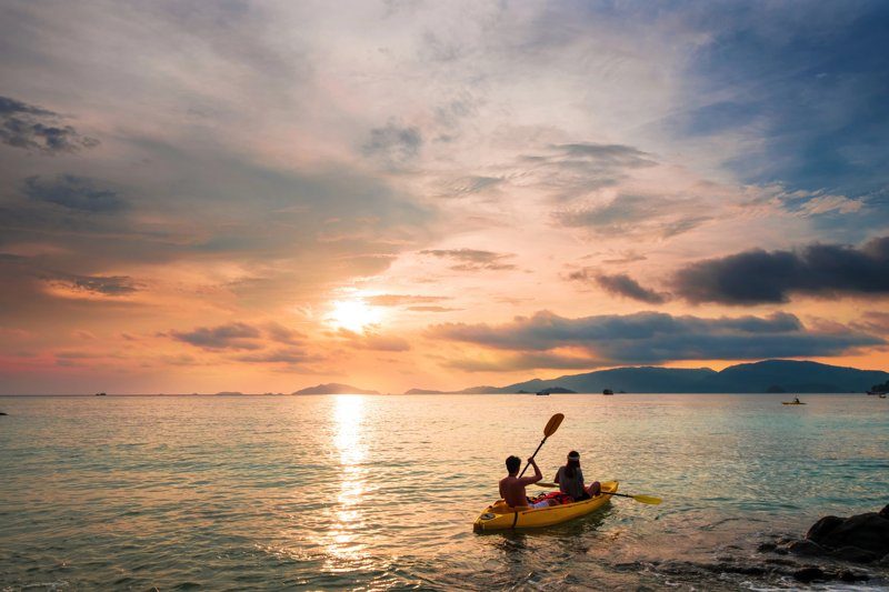 Deux personnes en kayak naviguant sur une mer calme lors d’un magnifique coucher de soleil.