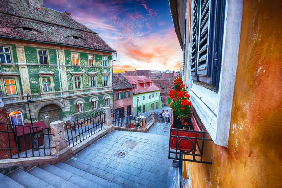 Passage des escaliers à Sibiu, Roumanie, au coucher du soleil avec des bâtiments colorés.