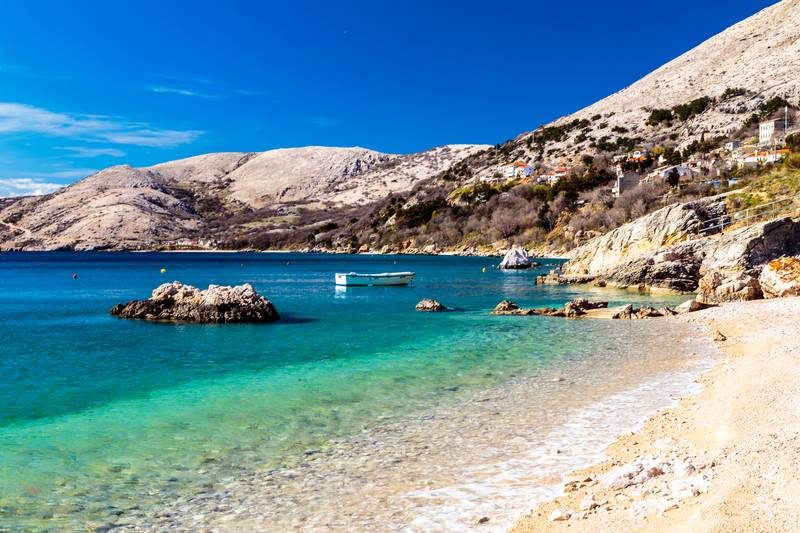Plage de galets avec mer turquoise.