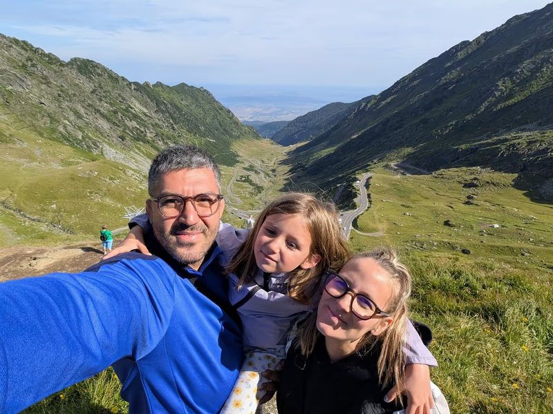 Nous 3 en selfie sur la route de Transfăgărășan, entourée de montagnes verdoyantes et d’un paysage spectaculaire.