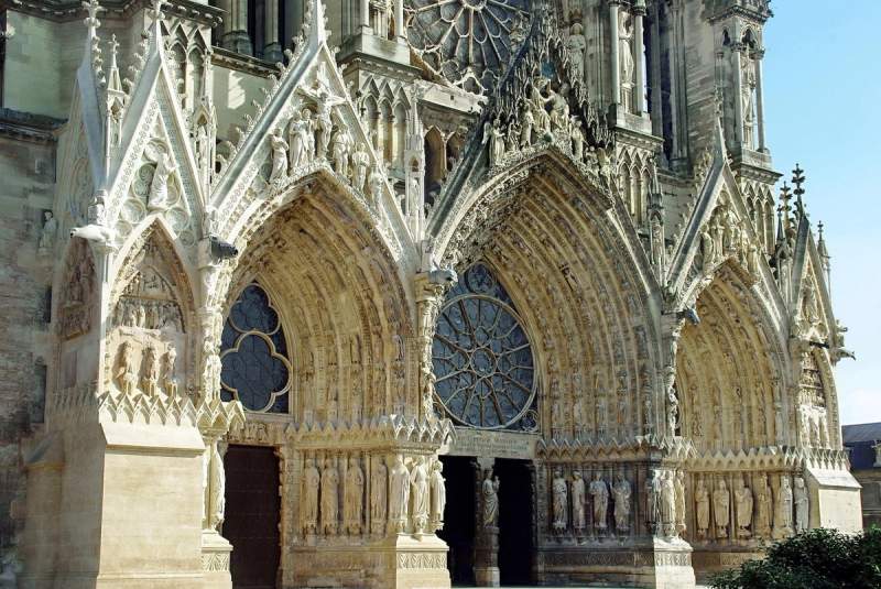 Façade de la cathédrale de Reims, France, montrant les détails architecturaux gothiques des portes et des sculptures.
