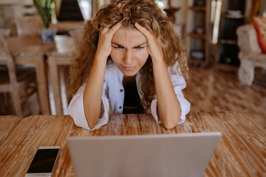 Une personne qui se tient la tête devant son PC
