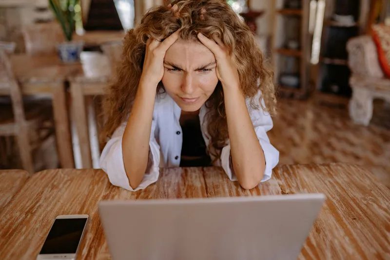 Une personne qui se tient la tête devant son PC