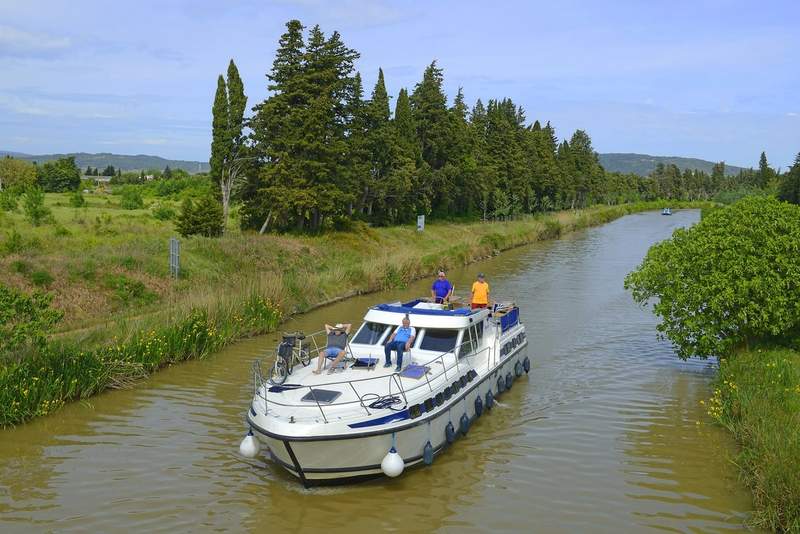 Groupe de voyageurs à bord d'une péniche en location sur le canal du Midi, navigation sans permis en pleine nature