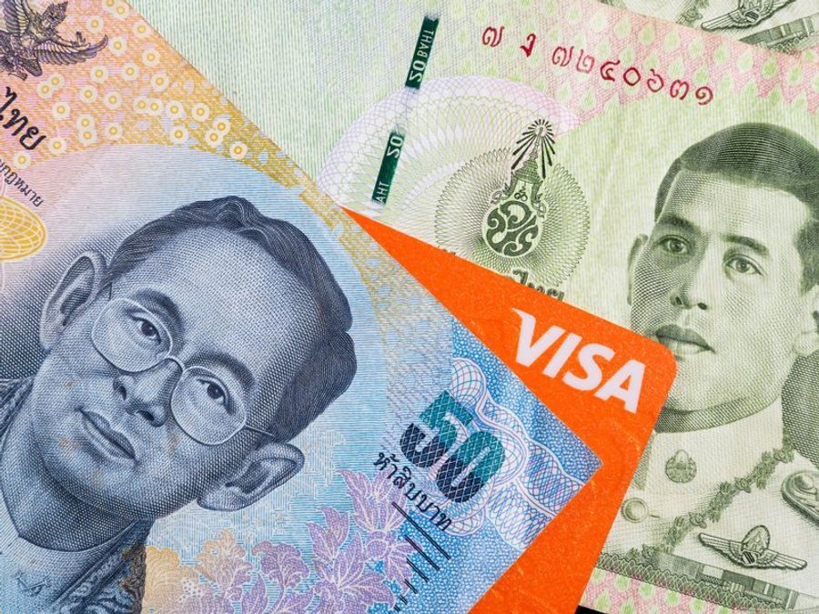 Carte Visa posée sur des billets de baht thaïlandais pour illustrer le paiement et le budget voyage en Thaïlande