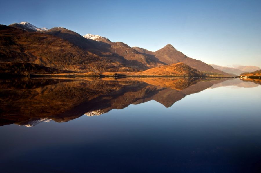 Montagnes de Glencoe se reflétant dans un loch au coucher du soleil