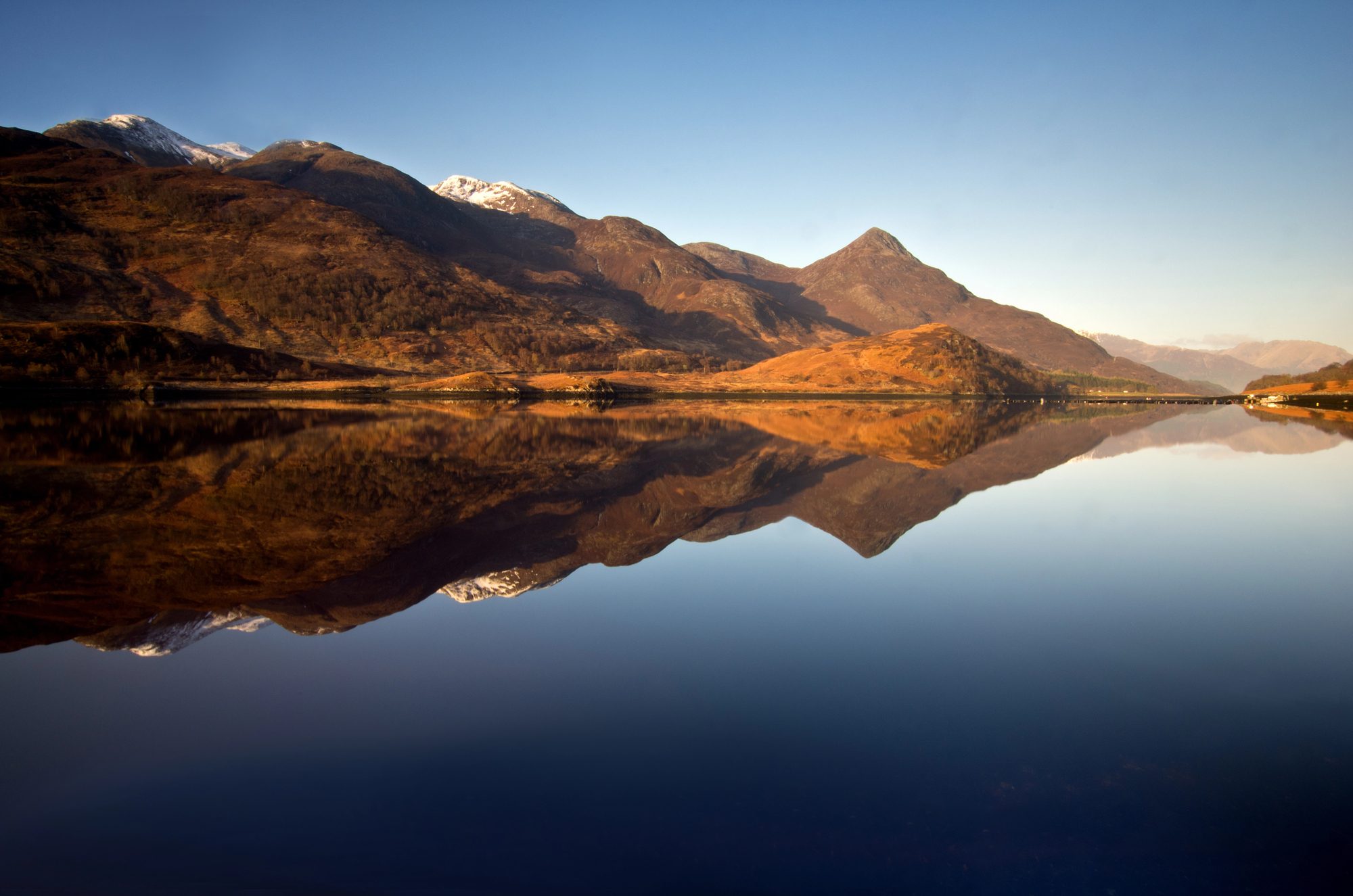 Montagnes de Glencoe se reflétant dans un loch au coucher du soleil