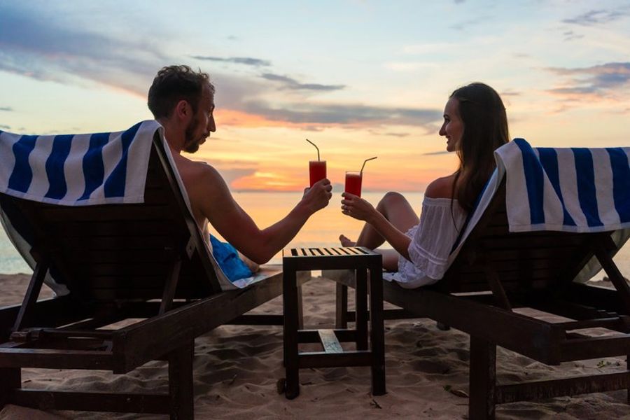 Un couple trinque avec des cocktails en bord de mer à Hiriketiya, Sri Lanka, au coucher du soleil.