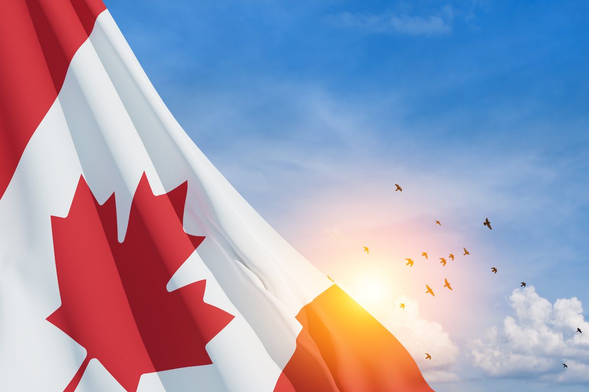 Drapeau du Canada flottant au vent avec un ciel bleu en arrière-plan, accompagné d'un coucher de soleil et d'un groupe d'oiseaux en vol
