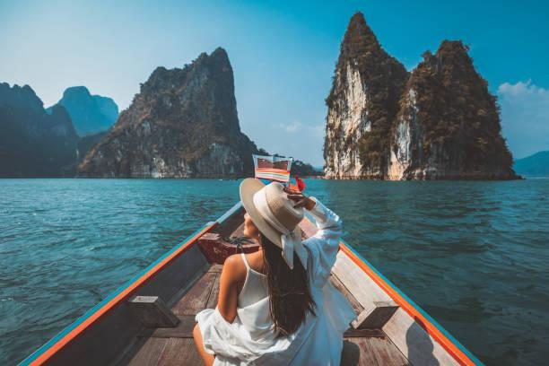 une femme asiatique voyageuse se détend et voyage sur un bateau thaïlandais à longue queue dans le barrage de ratchaprapha au parc national de khao sok surat thani thaïlande - voyage photos et images de collection