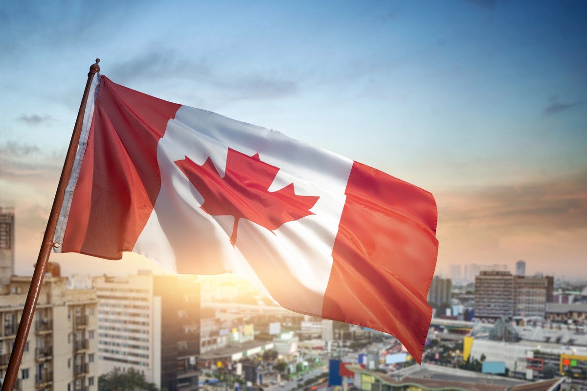 Drapeau du Canada flottant au-dessus d’une ville au coucher du soleil