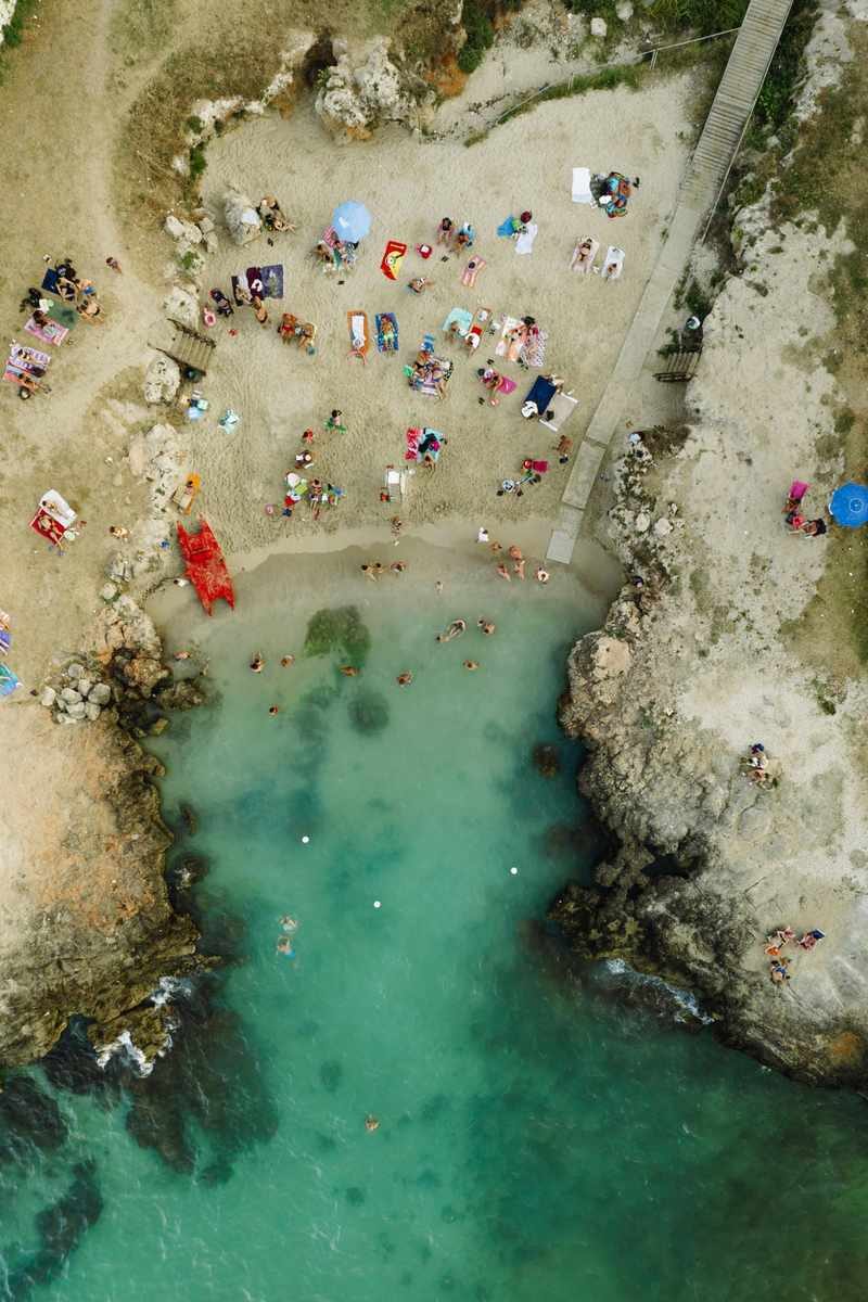 Vue aérienne de la plage Cala Paradiso à Monopoli, avec des baigneurs profitant du soleil et de l