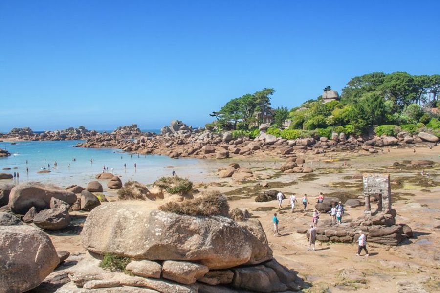 Plage pittoresque en Bretagne avec des gens profitant du littoral rocheux.