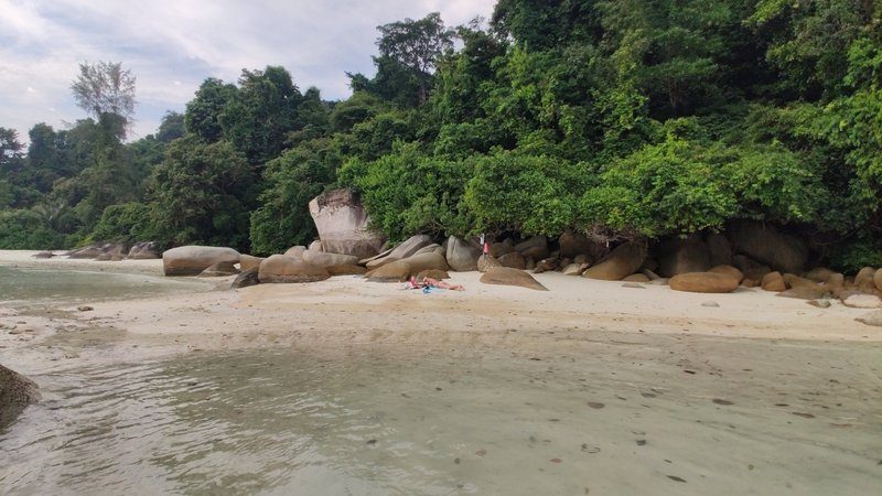 Petite plage isolée bordée de gros rochers et entourée de jungle tropicale aux îles Perhentian.