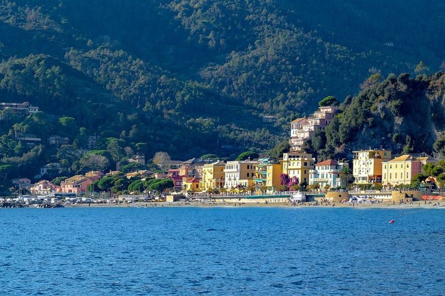  Vue panoramique de Monterosso avec ses maisons colorées le long de la plage et les collines verdoyantes en arrière-plan.