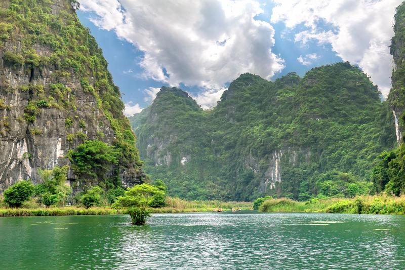 Paysage karstique spectaculaire de Tam Coc, avec rivière sinueuse entourée de formations calcaires verdoyantes.