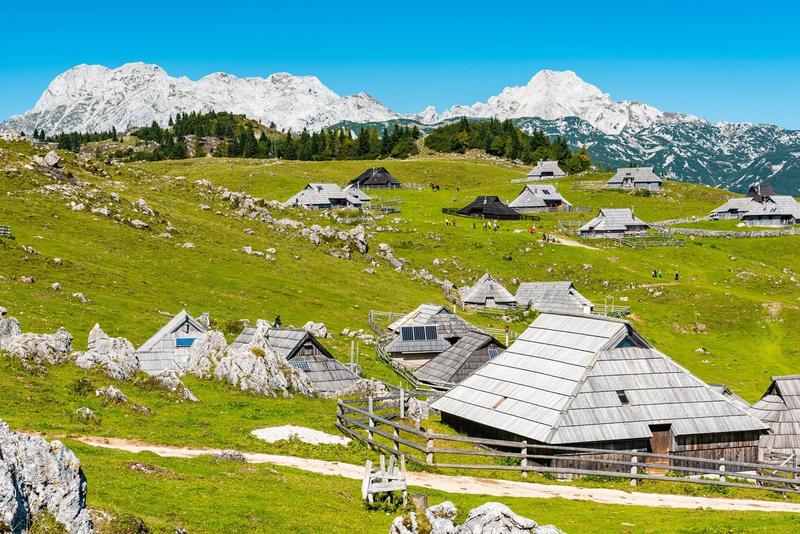 Vue des chalets traditionnels de Velika Planina en Slovénie avec les Alpes slovènes en arrière-plan.